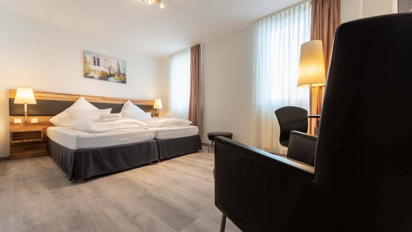 A hotel room with a double bed, bedside tables, a desk, and a chair.