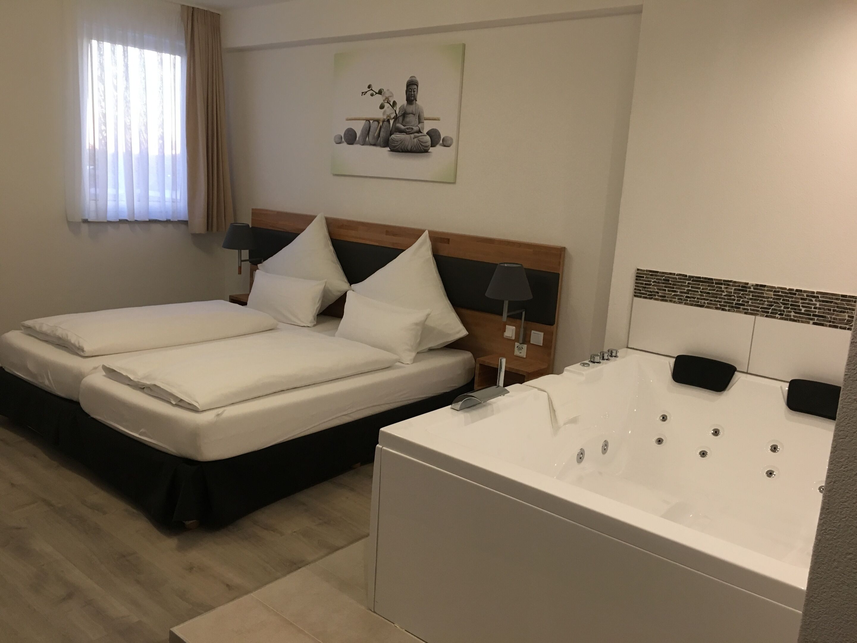 A hotel room with two beds, a large bathtub, and a wall-mounted artwork.