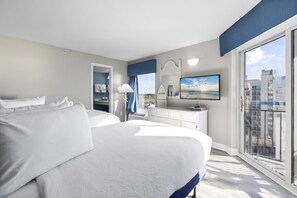 A modern hotel room with a large bed, a TV, a dresser, and a balcony with a city view. - Oceanfront Condo in the Heart of Myrtle Beach (Myrtle Beach)