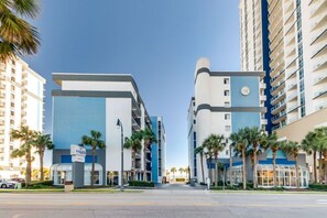 A modern hotel with a blue and white facade, palm trees, and a clear sky.