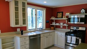 Une cuisine avec des meubles blancs, un lave-vaisselle, une cuisinière et un four à micro-ondes.