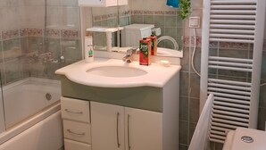 Ein Badezimmer mit einer Badewanne, einem Waschbecken mit Spiegel darüber, einer Toilette und einer Duschkabine.