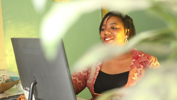 Una persona sentada en un escritorio con una computadora, un teclado y un ratón.