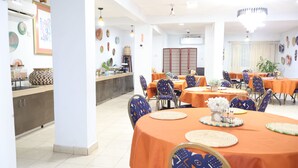 Un comedor con mesas redondas, sillas y una barra.