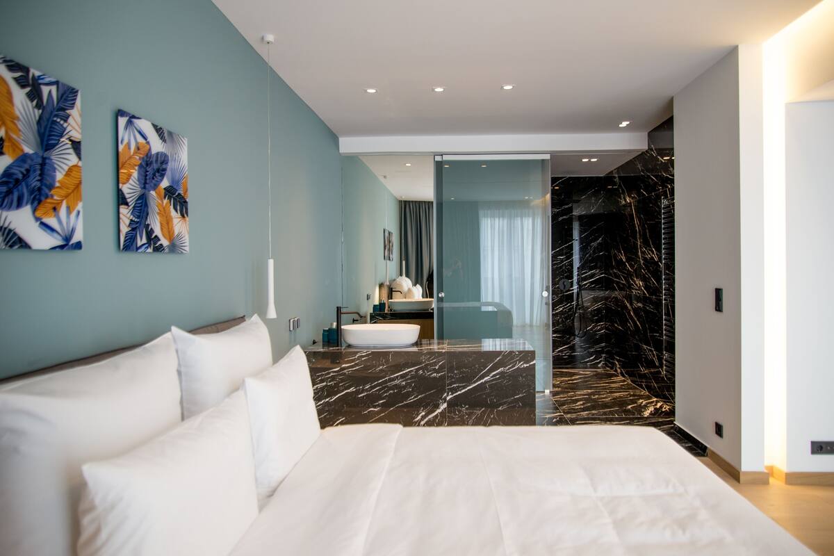 Ein modernes Schlafzimmer mit einem großen Bett, einem Marmorboden und Bildern an den Wänden.