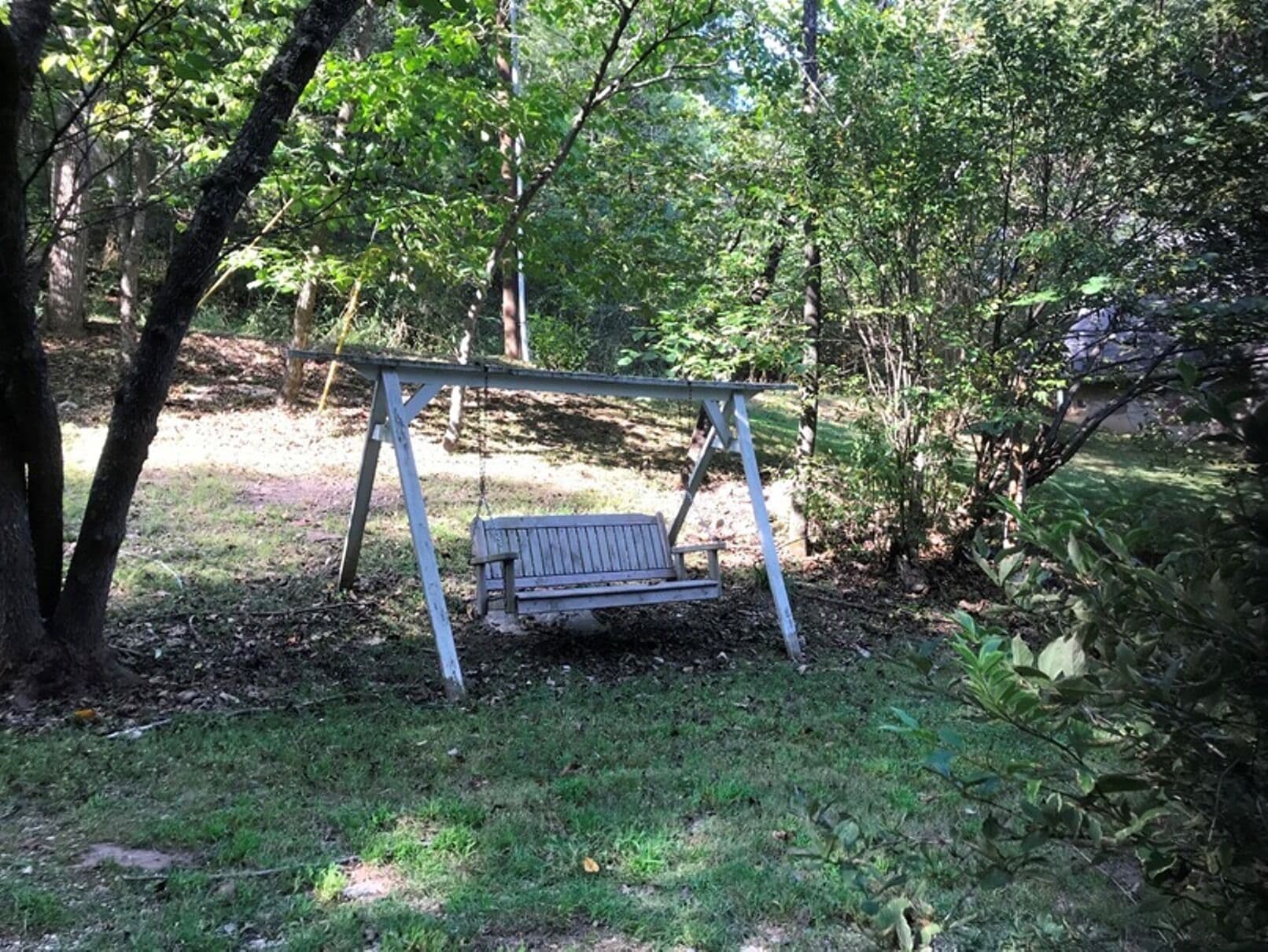 En gungställning i trä, placerad i ett skogsområde.