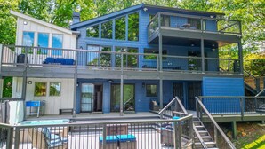 A multi-story house with a deck, outdoor seating, and a staircase.