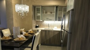 Une cuisine moderne avec un coin repas, comprenant un lustre, des placards et un réfrigérateur.