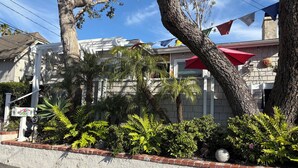A residential building with a white exterior, a brick base, and a red umbrella. - Exquisite L.B. House Within Walking Distance to Beach and Town (Laguna Beach)