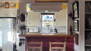 A kitchen with a central island, bar stools, a decorative painting, and a window with a view. - Exquisite L.B. House Within Walking Distance to Beach and Town (Laguna Beach)