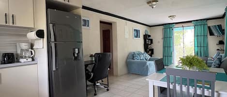 A compact kitchen with a refrigerator, a coffee maker, and a dining area with a table and chairs.