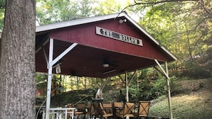 A covered pavilion named "The Hollow" with outdoor seating and a rustic design. - Room 3-Historic Little Switzerland - (Jasper)