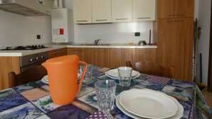 Une cuisine avec des meubles de rangement en bois, une cuisinière à gaz et une table mise pour le repas.