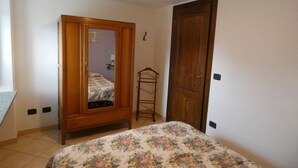 Une chambre à coucher avec un lit, une armoire en bois, un miroir et une porte.