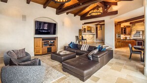 A spacious living area with a large leather sofa, a stone-tiled floor, and wooden beams on the ceiling. - Soquel Villa - 180 views of Monterey Bay w/ infinity pool, spa & movie theater (Soquel)