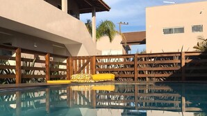 Una piscina con muelle de madera y un edificio al fondo.