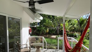 A covered outdoor area with a ceiling fan, a wicker chair, a glass table, and a red hammock. - Aves Hotel & Resort - Retreat Center (Cóbano)