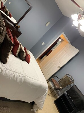 Cozy retreat with a large bed, dresser, and TV.