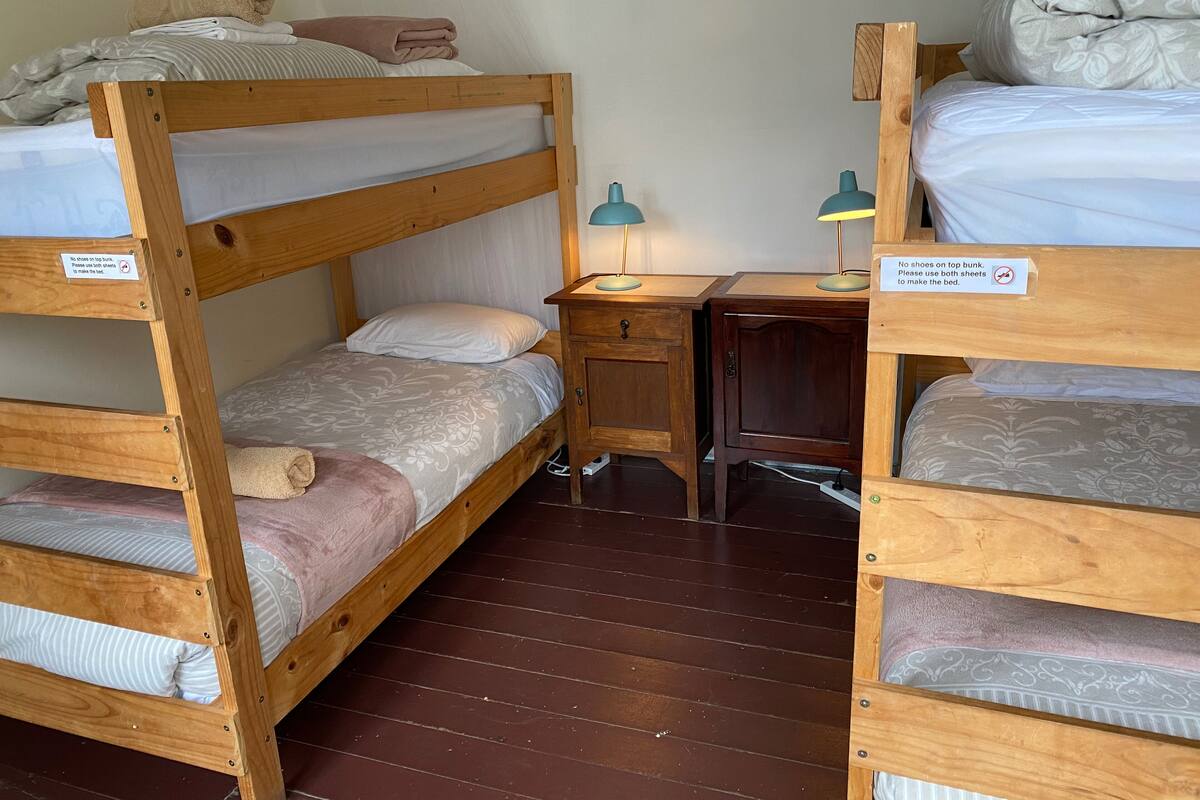 Habitación con literas, un escritorio y dos lámparas.