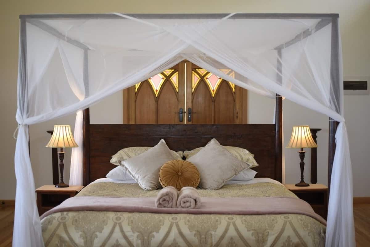 Una cama con dosel, dos lámparas de noche y un cabecero de madera.
