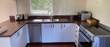 A modern kitchen with a dishwasher, sink, microwave, and stove.