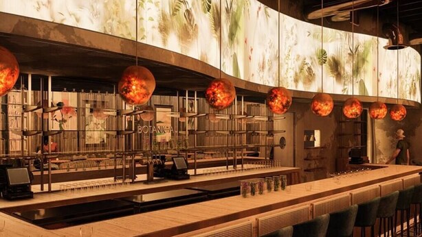 A bar area with a long counter, bar stools, and a large screen displaying floral patterns.
