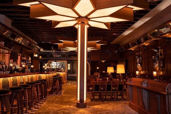 A bar area with wooden bar stools, a central pillar, and overhead lighting. - North Park Retreat | Trendy | Tranquil | Vibrant (San Diego)
