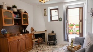 A cozy living room with a fireplace, wooden furniture, and a view of the outside balcony.