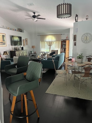 A living room with a sofa, chairs, a coffee table, a TV, and a bookshelf.