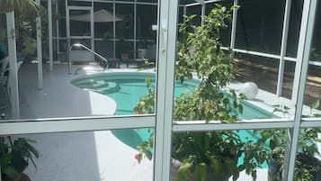 Un espace extérieur abrité comprenant une piscine, des sièges et des plantes en pot.