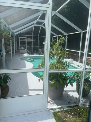 Un espace extérieur abrité comprenant une piscine, des sièges et des plantes en pot.