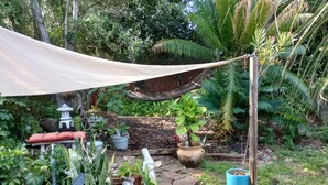 Un jardín con plantas en macetas, un sendero de piedra y una zona con sombra.