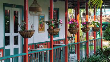 A covered outdoor seating area with hanging planters and a red and green railing.