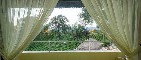 Habitación con vista a un paisaje verde a través de cortinas translúcidas.