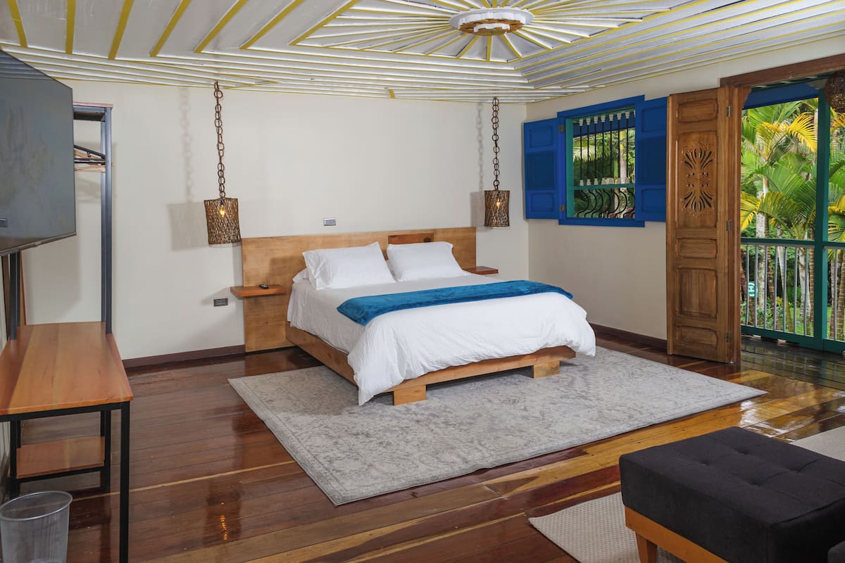 A bedroom with a wooden bed, a nightstand, a desk, and a TV.