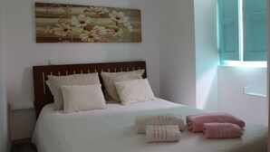 A bedroom with a bed, pillows, a painting, and towels. - Green house with pool (Nadadouro)