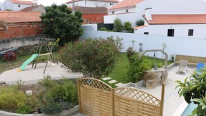 A courtyard with a wooden gate, a swing set, a small pool, and a garden area. - Green house with pool (Nadadouro)