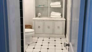 A bathroom with a white vanity, a toilet, and a tiled floor.
