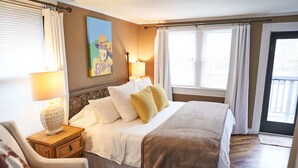 A bedroom with a bed, bedside tables, a lamp, a chair, and a painting on the wall.