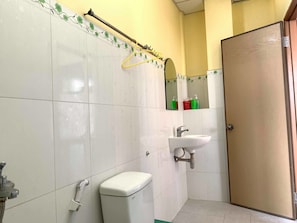 A bathroom with white tiled walls, a toilet, a sink, and a shower. - Hoang Hai Đang 1 Hotel (Can Tho)