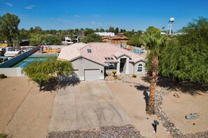 A residential property with a swimming pool, a garage, and a water tower in the background.