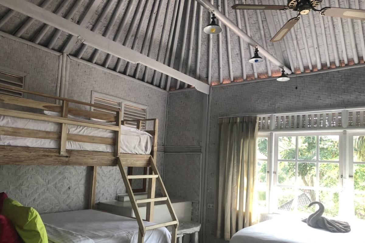 A room with bunk beds, a ladder, a desk, a window with curtains, and a ceiling fan.