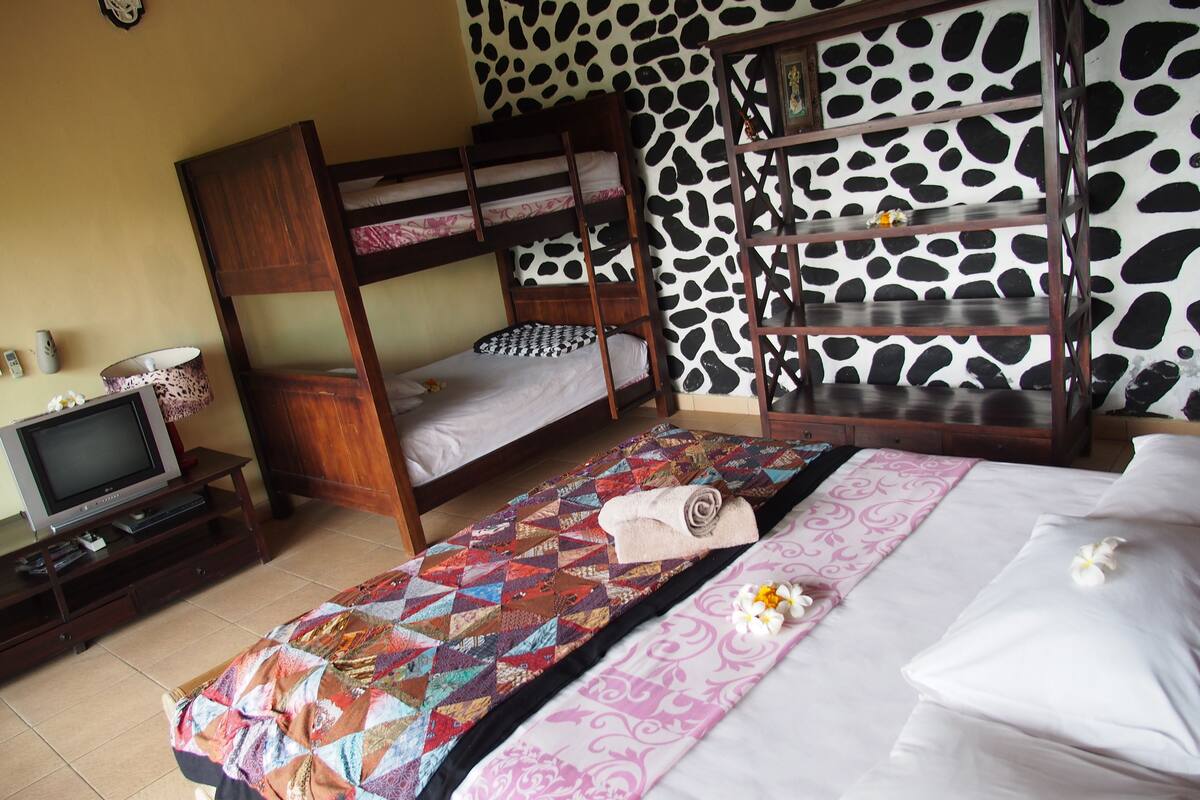 A room with bunk beds, a television, a patterned rug, and a cow print wall.