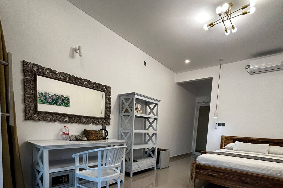 A modern bedroom with a bed, a desk with a chair, a wardrobe, and a mirror.