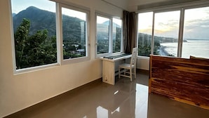 A spacious room with large windows offering a view of a mountainous landscape and a body of water. - Waenis Sunset View (Karangasem)