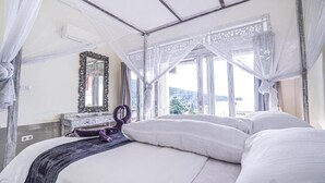 A bedroom with a canopy bed, a dresser, and a mirror. - Waenis Sunset View (Karangasem)