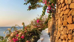 A stone wall with a curved pathway leading to the sea. - Waenis Sunset View (Karangasem)