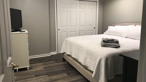 A bedroom with a bed, a television on a dresser, and a door. - Tranquil Escape~Modern 1BD Suite on Greenway (Charlotte)