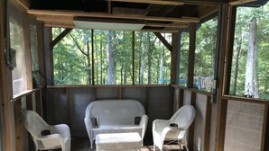A covered porch with two wicker chairs and a bench, wooden beams, and a view of a forest. - Tranquil Escape~Modern 1BD Suite on Greenway (Charlotte)