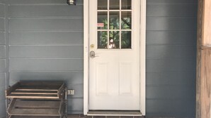A white door with a glass panel, a small step leading up to it, and a wall-mounted light fixture. - Tranquil Escape~Modern 1BD Suite on Greenway (Charlotte)